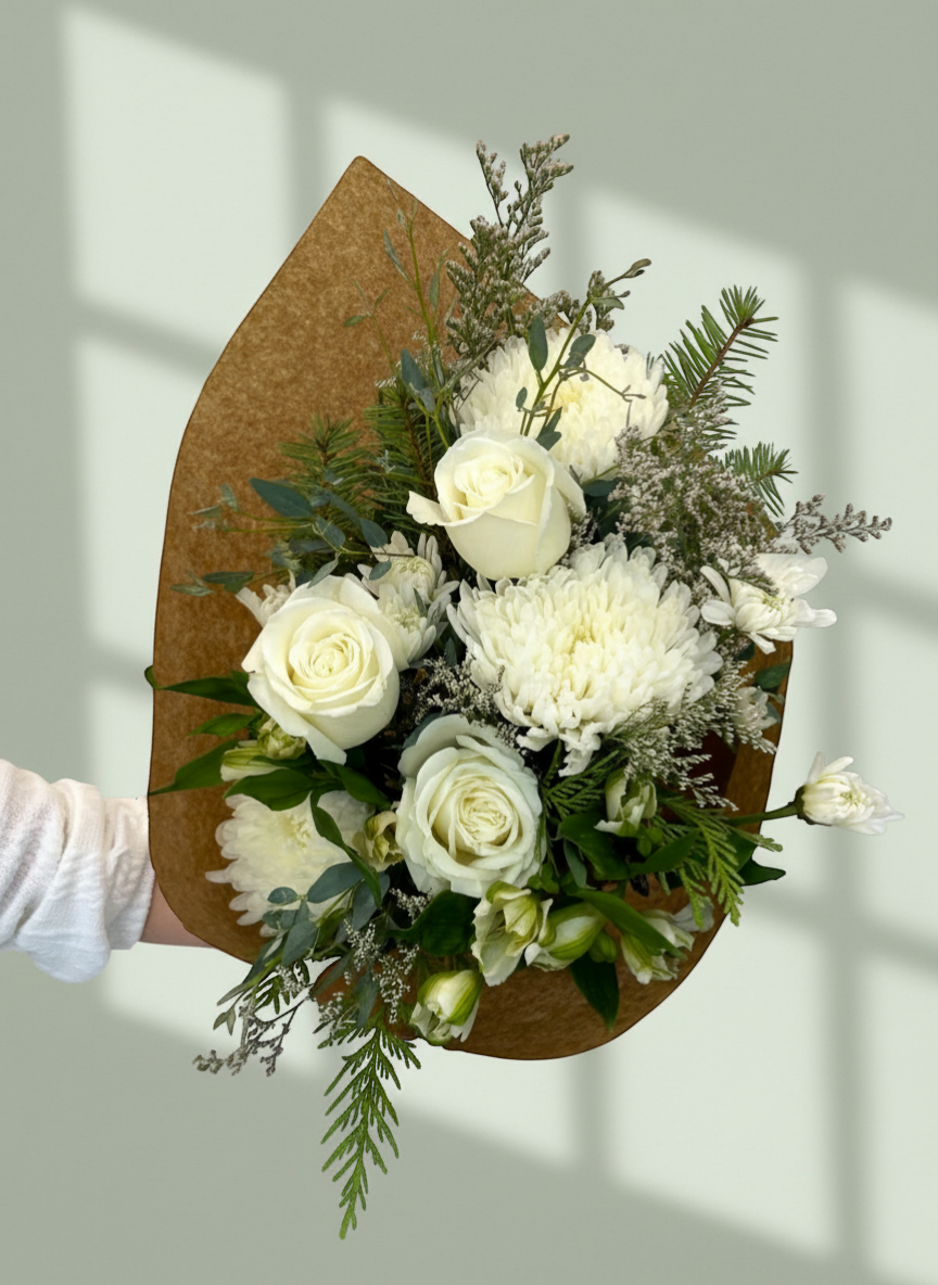 Lakewood Florist Winter Whites Bouquet: white roses, chrysanthemums, and winter greens in brown paper wrap.